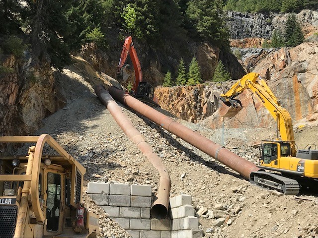 IWC Excavation - Ore Chute - Excavators placing steel pipe in place to crushing facility