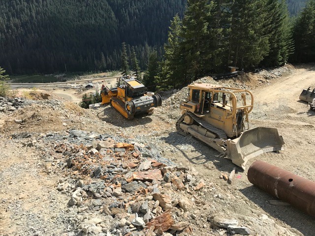 IWC Excavation - Ore Chute - Remote-Operated Bulldozer tethered to dozer to hold steel pipe in place